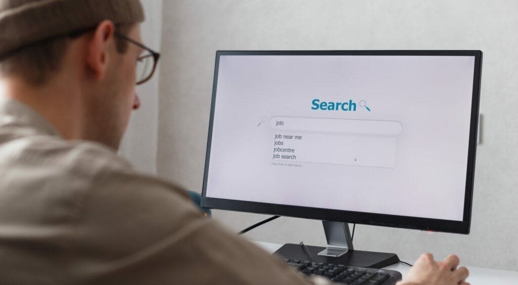 Unemployed man looking for work on the internet sitting at the computer at home