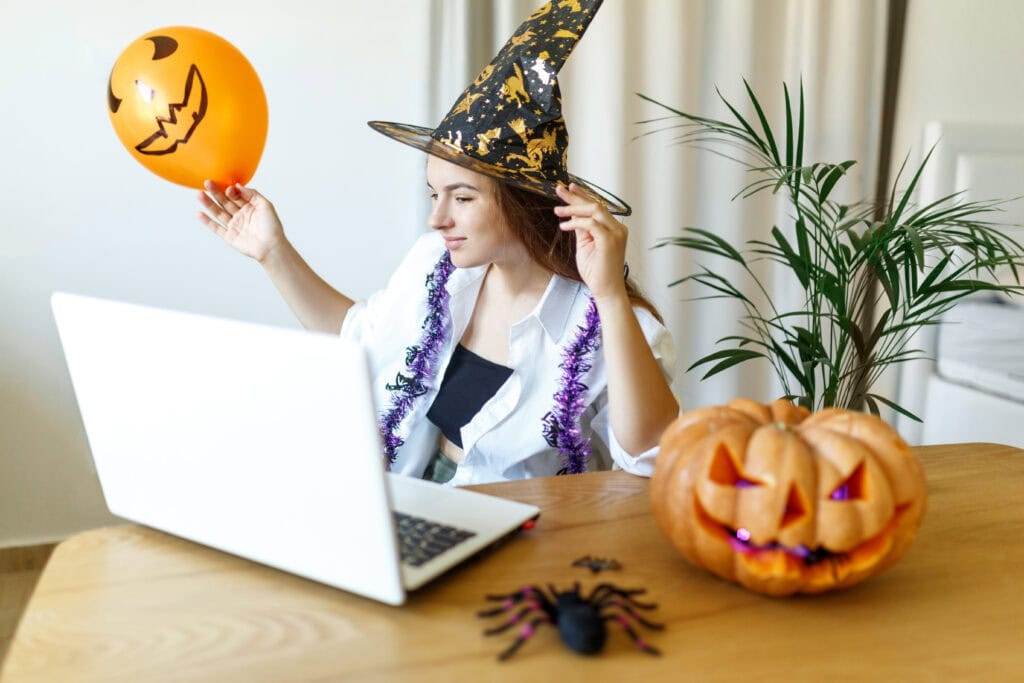 A woman in a Halloween costume smiling during a virtual Zoom meeting.